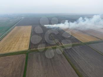 Burning straw in the fields after harvesting wheat crop. The burning of rice straw in the fields. Smoke from the burning of rice straw in checks. Fire on the field.