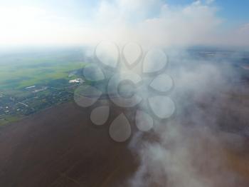 The smoke over the village. Clubs of smoke over the village houses and fields. Aerophotographing areas.