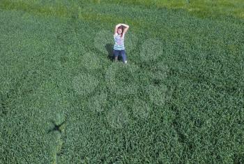 The girl in the middle of young wheat field and shadow from quadrocopters on the grass.