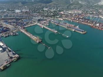 Industrial seaport, top view. Port cranes and cargo ships and barges. Loading and shipment of cargo at the port. View of the sea cargo port with a bird's eye view.