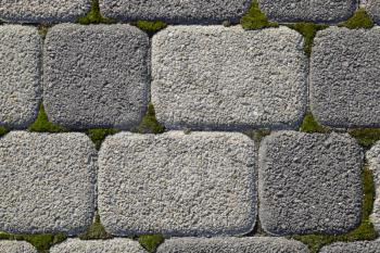 Industrial building background of paving slabs with overgrown with moss in the cracks. Texturing background.