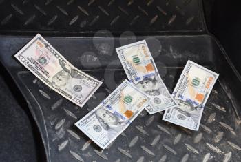 Several banknotes American dollars lie on the mat for a car down. The money in the car. Dollar fell to the floor.