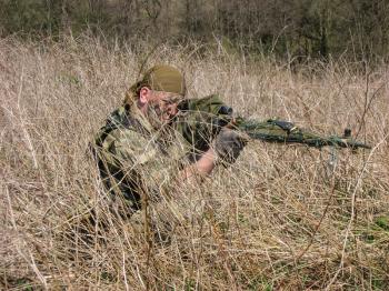 Fighter of special troops. Sniper rifle Dragunov hidden in dry grass, and aiming at a target.