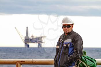 Oilman shift workers on the deck of the ship on the background offshore oil shelf planforms. Work on the way to work.