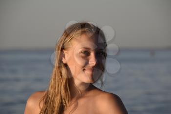 Blond girl in a bikini standing in the sea water. Beautiful young woman in a colorful bikini on sea background.
