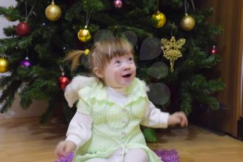 One year old baby girl sitting on the floor near a Christmas tree .. A child plays. Blonde little girl.
