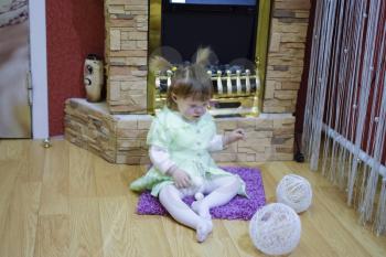 One year old baby girl sitting on the floor. A child playing with wicker balls. A blonde girl.