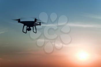 Quadrocopters silhouette against the background of the sunrise. Flying drones in the evening sky.