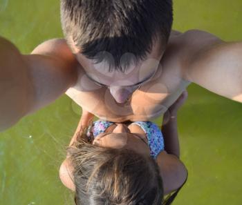 Man and woman doing selfie standing in the green sea water. Young girl hugging a guy.