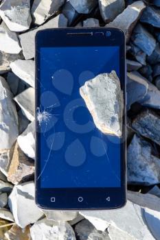 Frustrated phone on the rocks. Glass shattered on rocks on a smartphone. Smartphone fell and crashed.