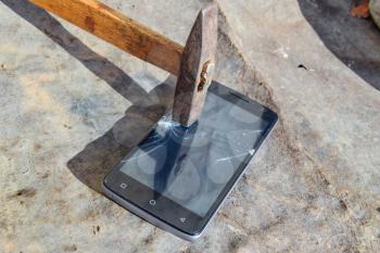 Hammer and smartphone. The screen of the smartphone, a broken hammer. The destruction of the phone.