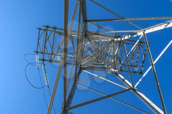 Supports high-voltage power lines against the blue sky. View from the bottom up.