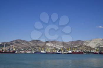 international seaports. Cargo port with port cranes. Sea bay and mountainous coast.