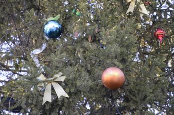 Decorations New Year tree. Tinsel and toys, balls and other decorations on the Christmas Christmas tree standing in the open air.