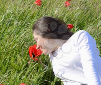 Beautiful fairy young girl in a field among the flowers of tulips. Portrait of a girl on a background of red flowers and a green field. Field of tulips.
