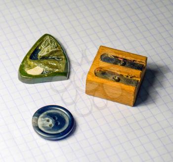On a sheet of notebook pencil sharpener, a button and a stone amulet.