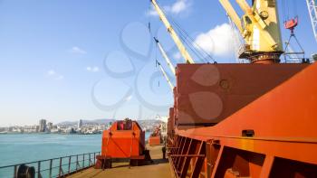 View of the sea and city beach from the port quay. Industrial port with tower cranes and cargo infrastructure.
