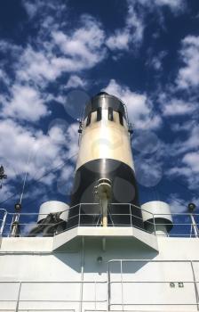 Pipe on the ship. White ship with a black chimney against the sky with clouds.
