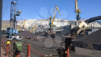 Cargo industrial port, port cranes. Loading of anthracite. Transportation of coal. Heap of coal.