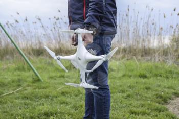 A man with a quadrocopter in his hands. A white drone is being prepared for the flight. Phantom