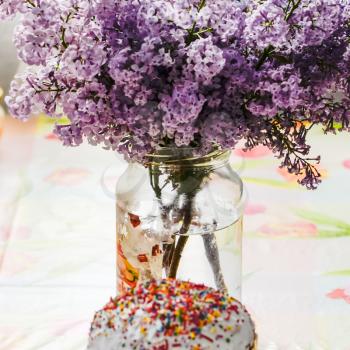 Bouquet of lilacs near Easter cakes and colored eggs
