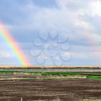 Rainbow, a view of the landscape in the field. Formation of the rainbow after the rain. Refraction of light and expansion in terms of spectra.