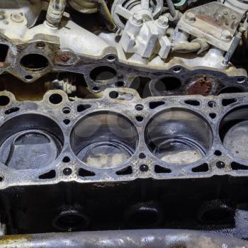 The cylinder block of the four-cylinder engine. Disassembled motor vehicle for repair. Parts in engine oil. Car engine repair in the service.