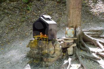 Orthodox candles in the forest under a tree in a box. The prayer stone by the road.