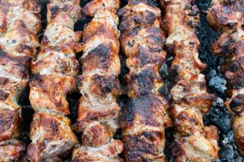 Frying pork on a skewer over a brazier. Turning meat over coals. Appetizing shish kebab. Delicious barbecue.