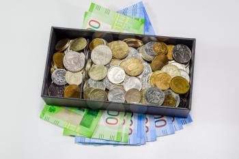 Coins of different denominations in a piggy bank box. Paper rubles under the piggy bank. New banknotes of Russia.