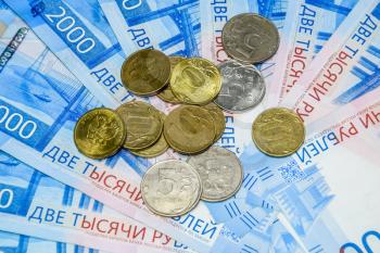 Russian banknotes and coins. A handful of coins on new Russian banknotes in denominations of 2000 and 200 rubles