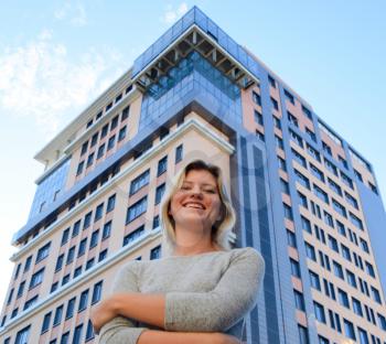 Portrait of a girl on the background of a multi-storey building. A girl with a beautiful figure in a gray dress near a tall building