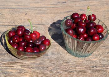 Berries of a sweet cherry in a glass bowl on a wooden background. Ripe red sweet cherry.