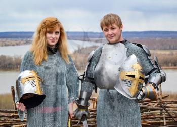 Knight with his wife in armor and chain mail. Knightly armor and weapon. Semi - antique photo.