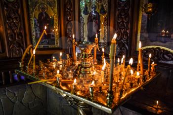 Burning candles on a stand near the icons in the chapel. Attributes of Orthodox Christianity.