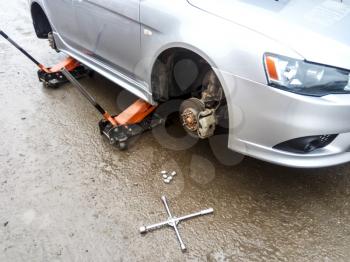 The car is at the tire shop. Under the jack the car in car-care center. The car with the removed wheel