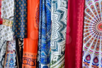 Indian fabrics hanging on the counter. Trade in fabrics from india. Fabric with patterns and patterns.