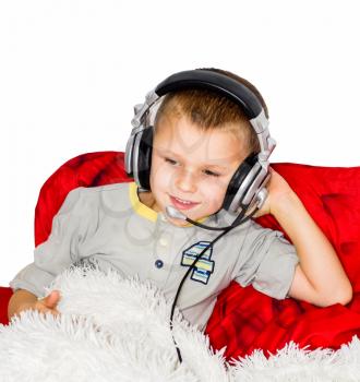 boy lies on the bed and listens to music with headphones