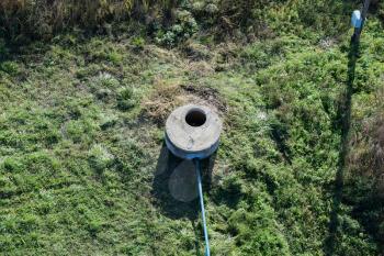 Well of an artesian well with a submersible pump. Covered with a concrete well