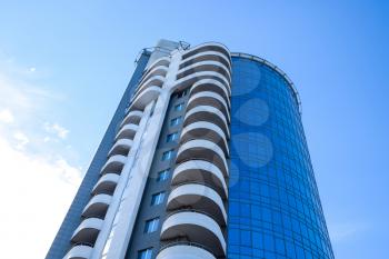 Residential building with balconies, multi-storey building. Building against the blue sky with clouds.