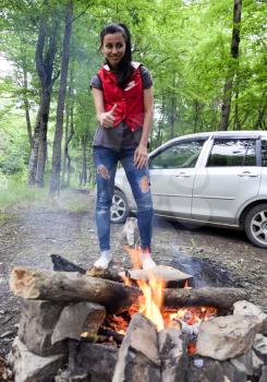 Nibirjay, Russia - June 24, 2017: A brunette girl by the fire in nature. Thumb Up