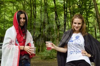 Nibirjay, Russia - June 24, 2017: Girls in the woods drink compote from plastic glasses.