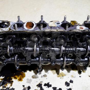 The head of the block of cylinders. The head of the block of cylinders removed from the engine for repair. Parts in engine oil. Car engine repair in the service.