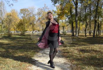 A woman is posing in front of a camera in an autumn park. autumn photo shoot. Autumn in the park.