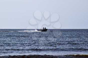 The boat rushes by the sea. In the boat people. Seascape in the evening. Silhouette of a motor boat and people in it against the background of the sea distance.