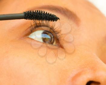 Girl Applying Mascara On Her Eyelashes Showing Cosmetics