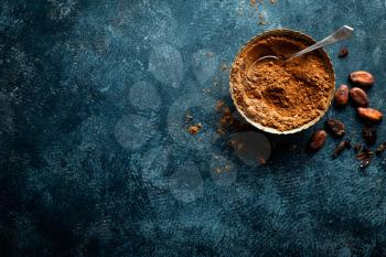 Cocoa powder and cacao beans on dark background, top view