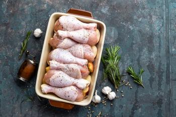 Raw uncooked chicken legs, drumsticks on wooden board, meat with ingredients for cooking, top view