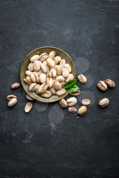 Pistachios nuts on dark background, top view, healthy snack