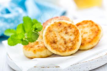 Cottage cheese fritters on white wooden background closeup